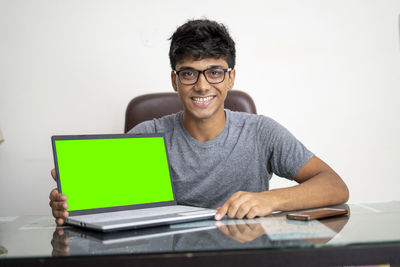 Young man using mobile phone while sitting on table