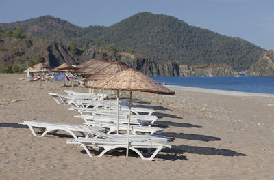 Deck chairs on beach against sky