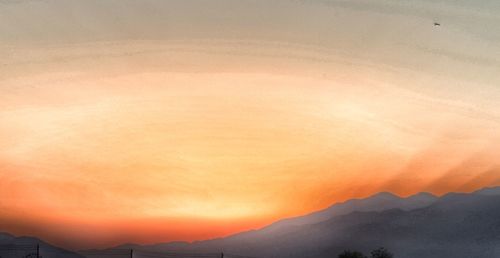 Scenic view of silhouette mountains against orange sky