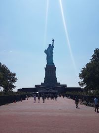 Statue of people in city against sky