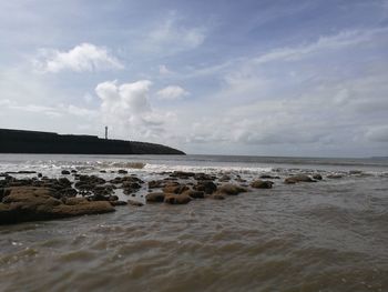 Scenic view of beach against cloudy sky