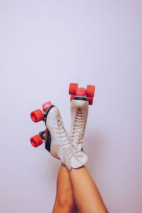 Legs up in the air wearing white skates with red wheels