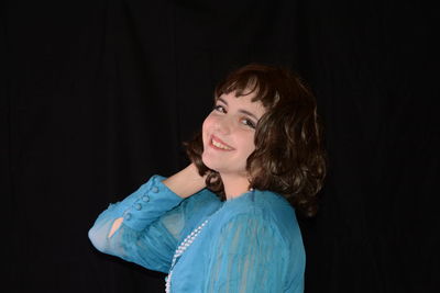 Portrait of a smiling young woman over black background