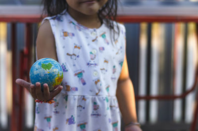 Midsection of woman holding globe on table