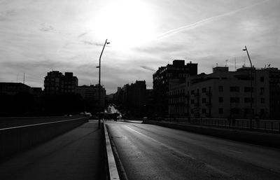 Road amidst buildings in city against sky