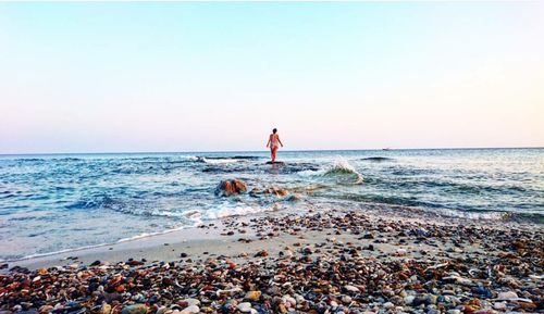 Man standing on beach against clear sky