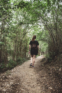 Rear view of woman walking on footpath in forest