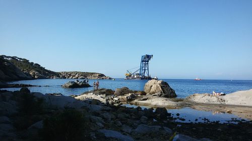 Rocky sea shore against clear sky