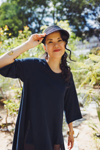 Middle-aged japanese woman in black straw sun brim hat, summer park