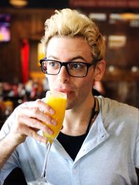 Young man looking away while drinking mimosa in bar