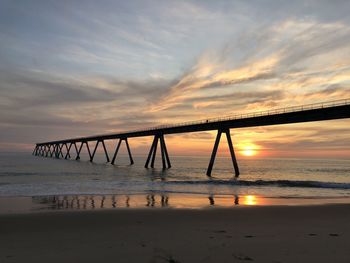 Silhouette pier on beach against sky during sunset