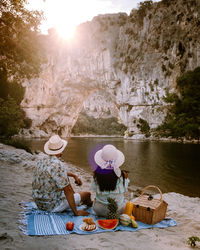 Woman sitting on rock by water