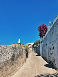 Footpath by building against clear blue sky