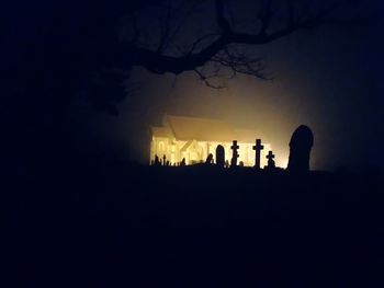 Silhouette people by tree against sky at night