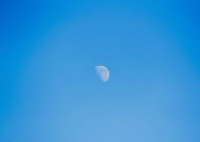 Low angle view of moon against clear blue sky