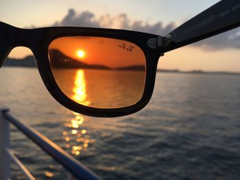 Close-up of sunglasses against sky during sunset