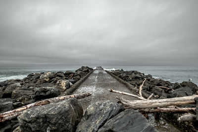 Scenic view of breakwater against grey sky