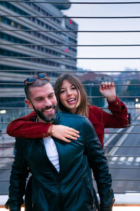 Portrait of happy woman with boyfriend standing on footbridge 