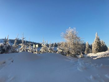 Snow covered landscape against clear blue sky