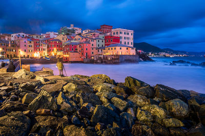 Buildings by sea against sky at dusk