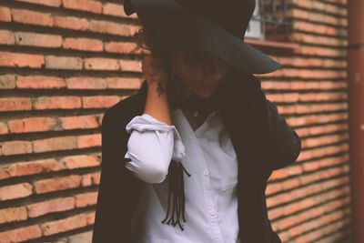 Midsection of woman standing against brick wall