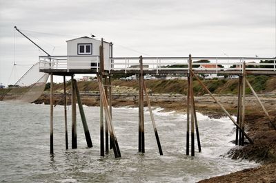 Wooden posts on beach by sea against sky