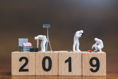 Close-up of figurine with wooden block on table