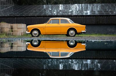 Yellow oldtimer on street during rainy season with reflection in the water 