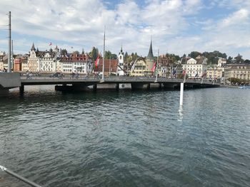 Bridge over river by buildings in city against sky