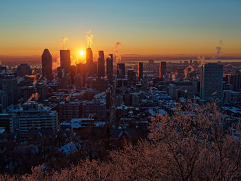 Aerial view of modern buildings in city against sky during sunset