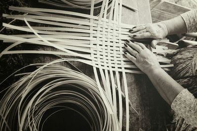 Cropped image of woman weaving basket on table