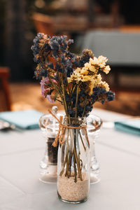 Autumn dried yellow blue flowers in a glass vase on the table
