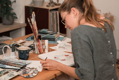 Side view of young woman painting at home