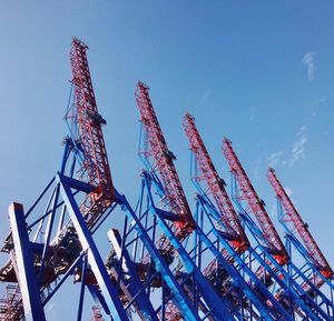 Low angle view of cranes against blue sky