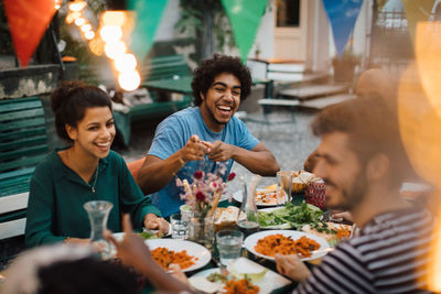 Cheerful male and female friends enjoying during dinner party in backyard