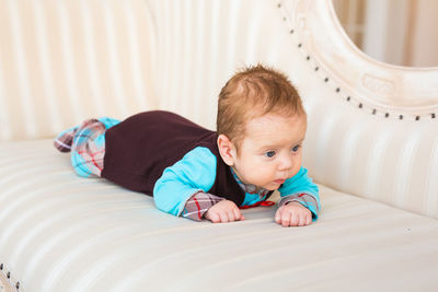 Portrait of cute baby lying on bed at home