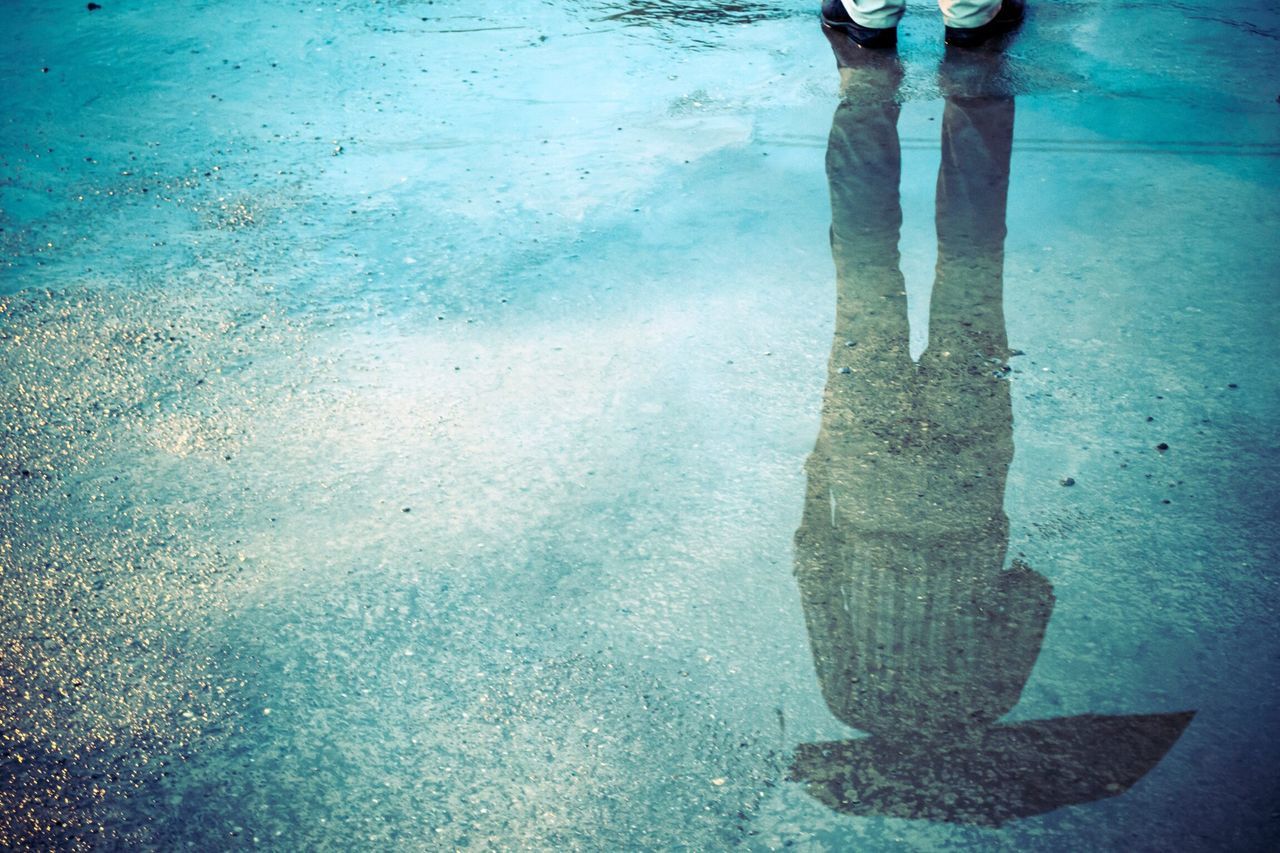 water, low section, reflection, person, puddle, high angle view, wet, shadow, street, standing, blue, sunlight, rain, day, lifestyles, unrecognizable person, human foot, outdoors