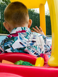 Rear view of boy riding toy car in garden