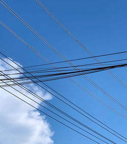 Low angle view of power cables against sky