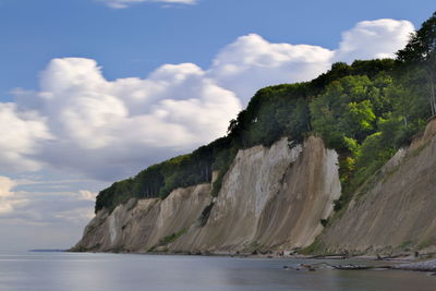 Scenic view of cliff at sea shore against sky