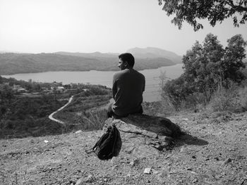 Rear view of man looking at mountains against sky
