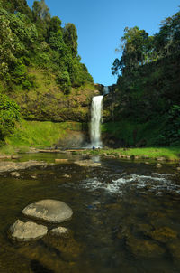 Scenic view of waterfall in forest against sky