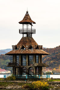 Traditional building by lake against sky