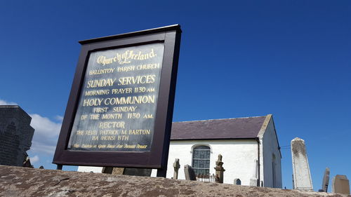 Low angle view of text on building against clear blue sky