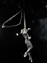 Low angle view of woman jumping against black background