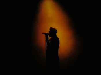 Silhouette man standing against orange sky