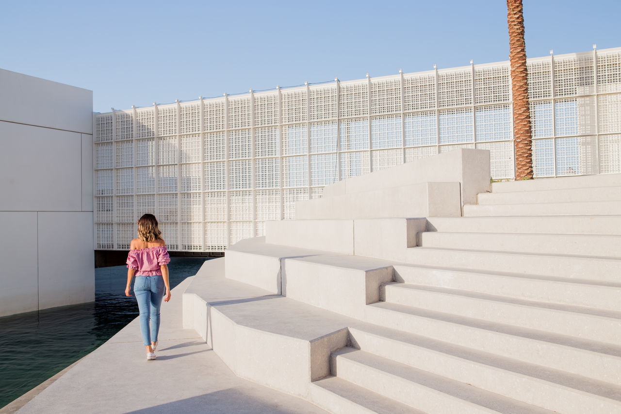 Rear view of woman standing on staircase against sky