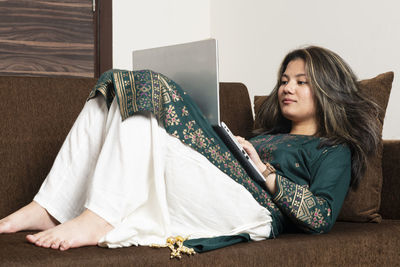 Portrait of young woman sitting on sofa at home