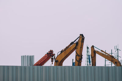 Low angle view of crane at construction site against clear sky