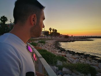 Side view of young man against sky during sunset